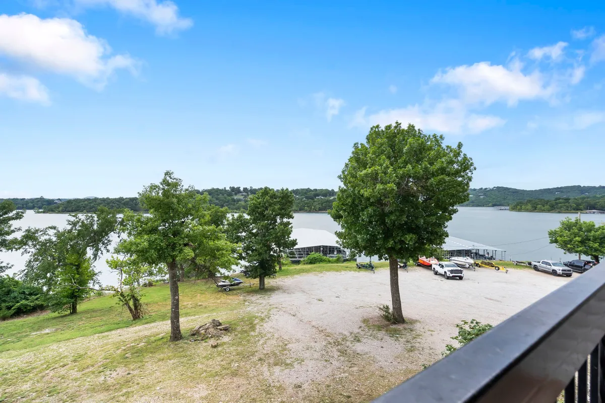 A scenic lake view surrounded by lush greenery, with parked vehicles suggesting accessibility and activity. Distant hills frame the backdrop, and the area invites outdoor adventures such as fishing, picnicking, boating, and nature walks. The tranquil mood is enhanced by the possibility of sunset watching, stargazing, and gathering around a campfire.