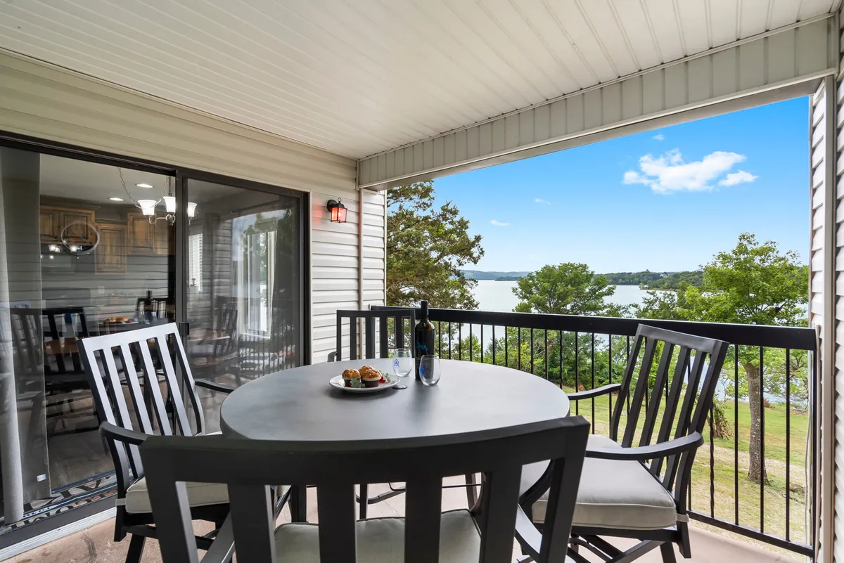 An outdoor dining table set for a meal overlooking the lake, with a bottle of wine and plated food enhancing the inviting atmosphere. The view captures the sunset over the water, suggesting an ideal spot for relaxing after a day of lakeside adventure and enjoying the tranquil beauty of Table Rock Lake.